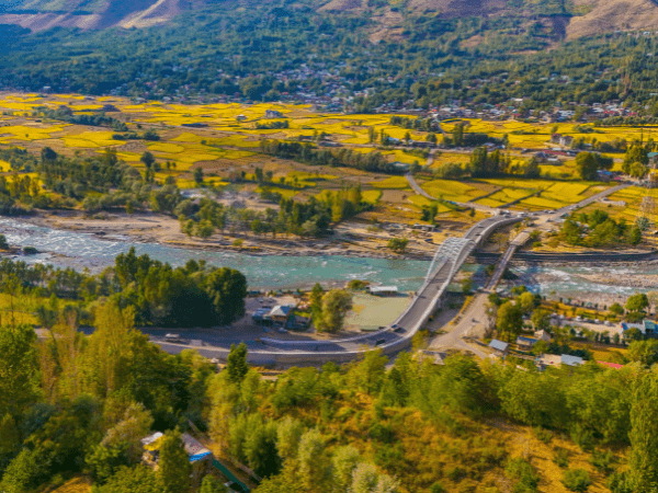 Aerial panorama of the Sind Valley in Kashmir, India, showcasing the Wayil Bridge over the Sindh River and surrounding mountains.