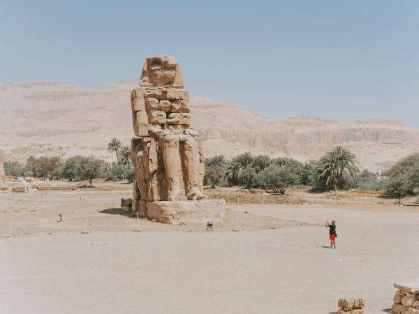 A tourist taking a picture of the Colossi of Memnon, highlighting expertly guided tours organized by a DMC in Egypt.
