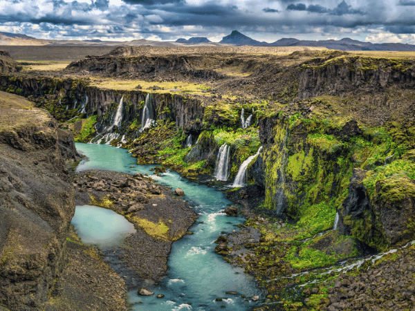 A dramatic Icelandic canyon with multiple waterfalls, highlighting adventure and exploration tours with a DMC in Iceland.