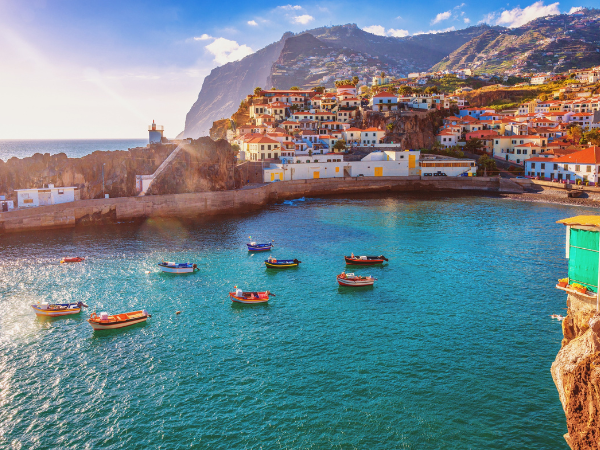 The picturesque harbor of Câmara de Lobos, Madeira, Portugal, with its vibrant fishing boats and colorful houses clinging to the hillside.