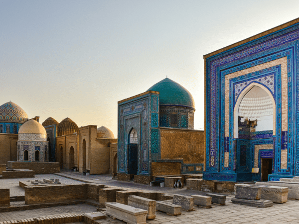 A group of mausoleums with blue tiled roofs in Shah-i-Zinda, Samarkand, Uzbekistan. In the background is the Bibi-Khanym Mosque.