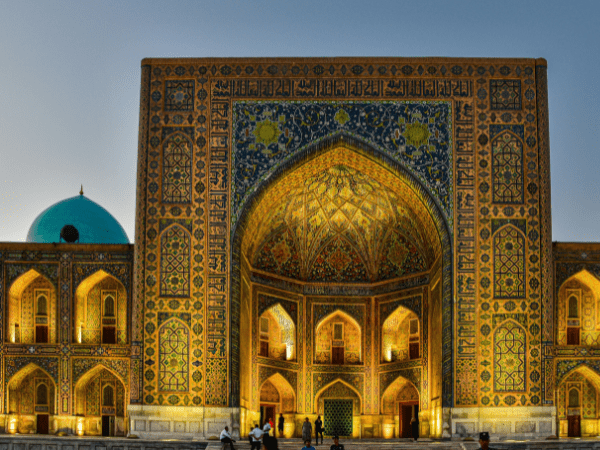 A large building with a blue dome on top, located in Registan Square, Samarkand, Uzbekistan