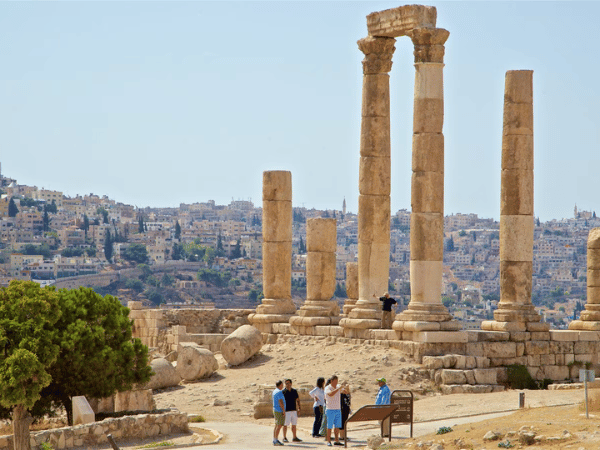 Tourists exploring the towering ancient columns at the Citadel in Amman, Jordan