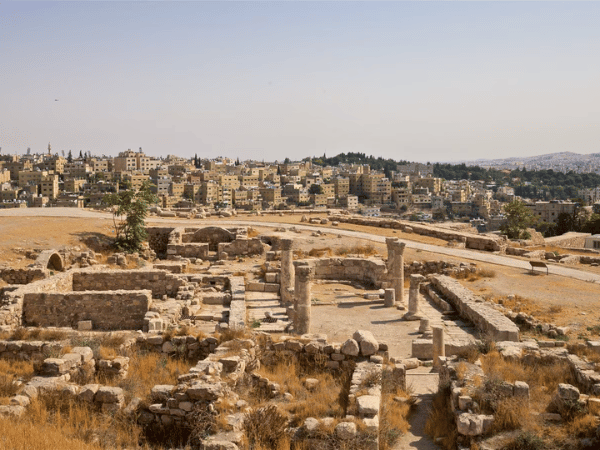 Ancient ruins with scattered columns and arches at the Citadel in Amman, overlooking the modern city.