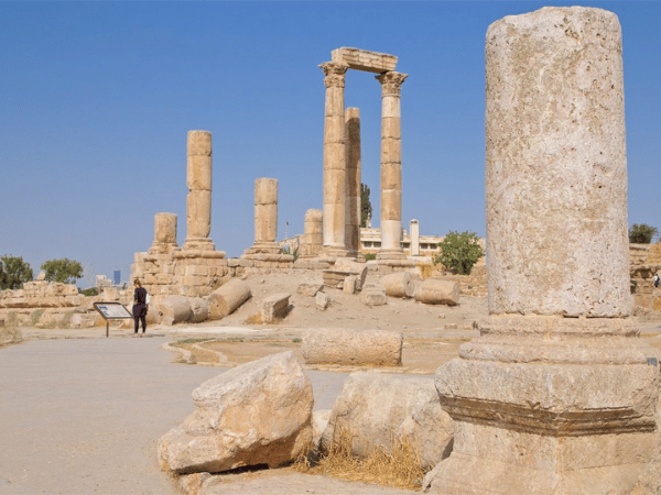 Visitor near the majestic columns and stone ruins at Amman Citadel, with a clear blue sky.