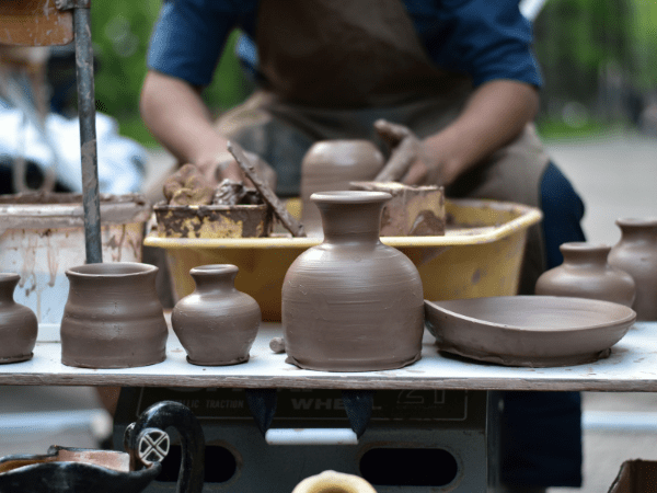 Kyrgyz artisan crafting clay pots on a pottery wheel.