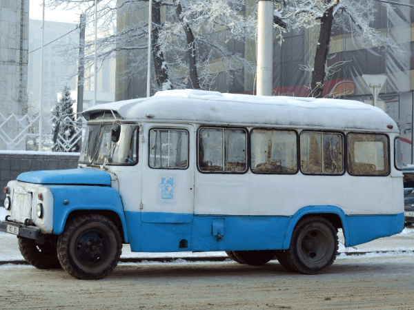 Blue and white bus parked on the side of a road in Kyrgyzstan